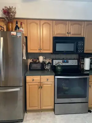 a kitchen with stainless steel appliances and wooden cabinets at House next to the golf course in Plantation