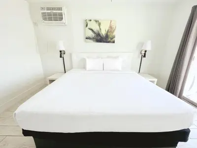 a white bed in a white room with two lamps at Tropi Rock in Fort Lauderdale