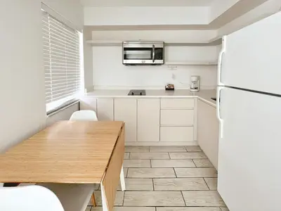 a kitchen with a wooden table and a refrigerator at Tropi Rock in Fort Lauderdale