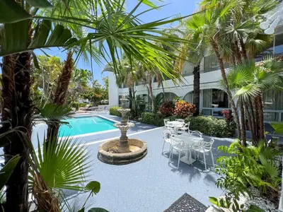 a courtyard with a fountain and tables and palm trees at Tropi Rock in Fort Lauderdale