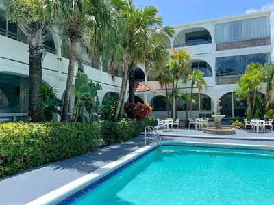 a swimming pool in front of a building with palm trees at Tropi Rock in Fort Lauderdale