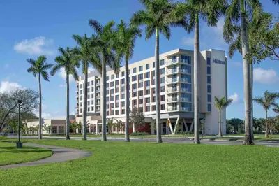 a building with palm trees in front of a park at Hilton Miami Dadeland in South Miami