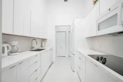 a white kitchen with white cabinets and a sink at Miami Brickell 4 Bedrooms High Ceiling loft on the pool in Miami