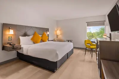 a hotel room with a large bed with yellow pillows at B&B Hotel Miami Airport in Miami