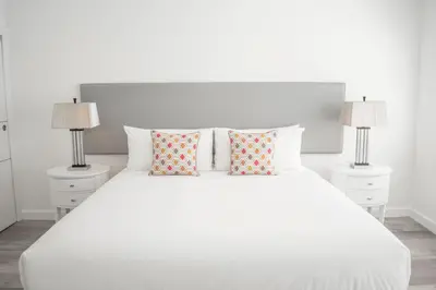 a white bedroom with a white bed with two lamps at Sobe Lux in Miami Beach
