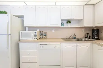 a white kitchen with white cabinets and a microwave at Luxury Miami Condos in Miami Beach
