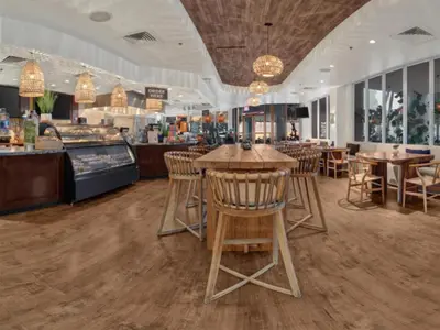 a restaurant with wooden stools and tables and chairs at Beach House Fort Lauderdale, A Hilton Resort in Fort Lauderdale