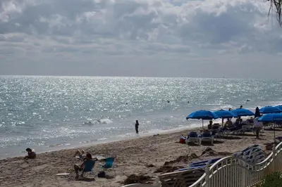 a beach with blue umbrellas and people on the beach at Direct Ocean View Condo at Tides of Hollywood - 7N in Hollywood