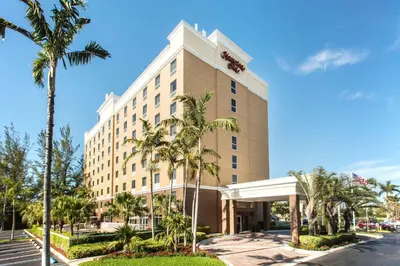 a hotel with palm trees in front of a building at Hampton Inn Hallandale Beach-Aventura in Hollywood