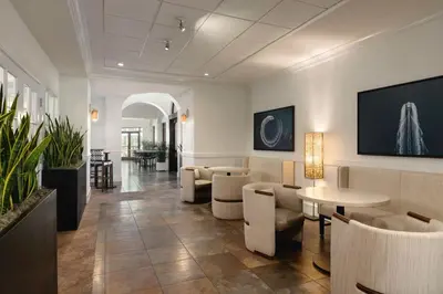 a lobby with a waiting room with tables and chairs at Embassy Suites by Hilton Fort Lauderdale 17th Street in Fort Lauderdale