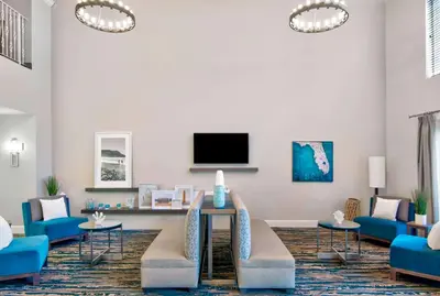 a living room with blue couches and a tv at Hampton Inn Ft Lauderdale Airport North Cruise Port in Fort Lauderdale