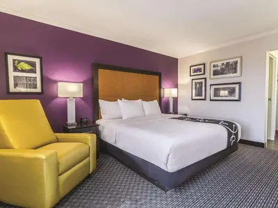 a hotel room with a bed and a yellow chair at La Quinta by Wyndham Miami Airport East in Miami