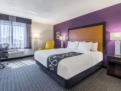 a hotel room with a large bed and purple walls at La Quinta by Wyndham Miami Airport East in Miami