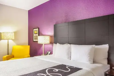 a hotel room with a large bed and purple walls at La Quinta by Wyndham Miami Lakes in Miami Lakes