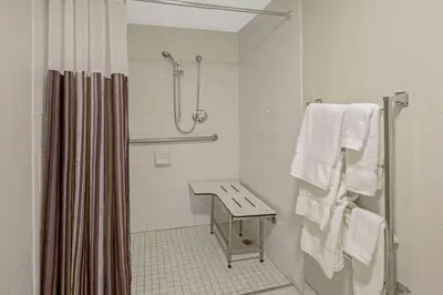 a bathroom with a shower and a sink and towels at La Quinta by Wyndham Miami Lakes in Miami Lakes