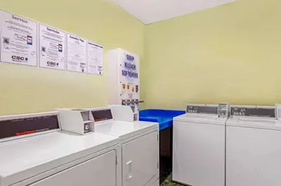 a laundry room with two machines and a blue bench at La Quinta by Wyndham Miami Lakes in Miami Lakes