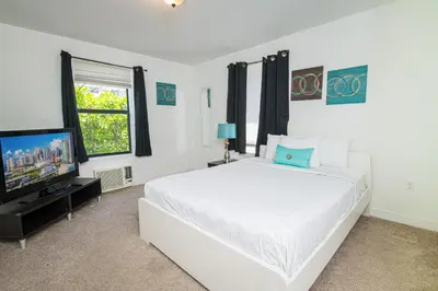 a white bedroom with a white bed and a television at Apartments in the Heart of Miami - Port of Miami / Miami Airport in Miami