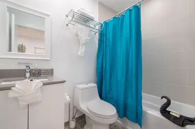 a bathroom with a toilet and a blue shower curtain at Renovated studio wocean view boardwalk steps in Hollywood