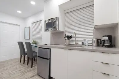 a kitchen with white cabinets and a table with chairs at Renovated studio wocean view boardwalk steps in Hollywood