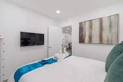 a bedroom with a white bed and a tv on the wall at Cozy apartment wsteps to beach boardwalk in Hollywood