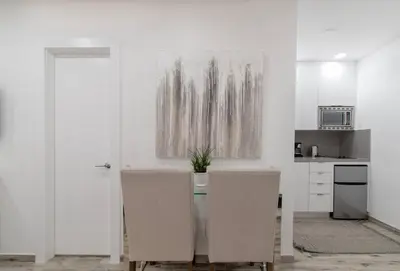 a white kitchen with a table and two chairs at Modern apartment wking bed beach views in Hollywood