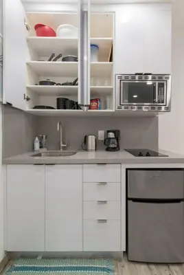 a white kitchen with a sink and a microwave at Renovated studio w ocean views boardwalk steps in Hollywood