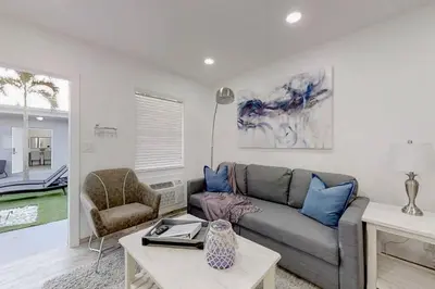 a living room with a gray couch and a chair at Modern apartment wking bed steps to beach in Hollywood