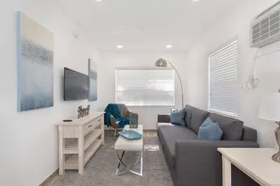 a living room with a couch and a table at Modern apartment wbeach steps parking in Hollywood