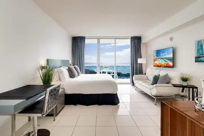 a hotel room with a bed and a couch at Ocean View Balcony steps from Restaurants, Peacock Park & Marina in Miami