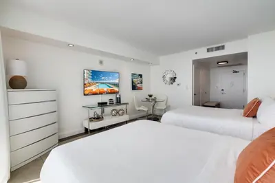 two beds in a bedroom with white walls at Ocean View Balcony steps from Restaurants, Peacock Park & Marina in Miami