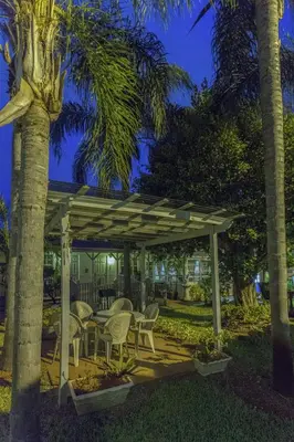 a gazebo with chairs and a table and palm trees at Richard's Motel Extended Stay in Hallandale Beach
