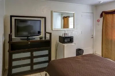 a bedroom with a television and a small refrigerator at Richard's Hotel in Hollywood