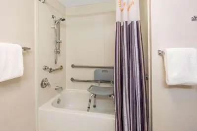 a bathroom with a bath tub with a chair in it at La Quinta by Wyndham Ft. Lauderdale Plantation in Plantation