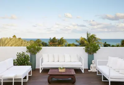 a patio with white furniture and the ocean at The Betsy Hotel, South Beach in Miami Beach
