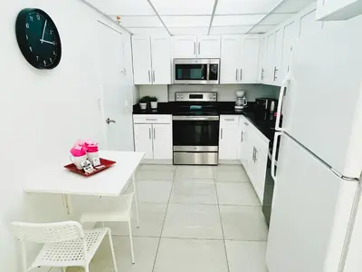 a white kitchen with a table and a refrigerator at Miami Hallandale Condo, Partial Ocean View Direct Beach and Pool Access Miami Hollywood Beach in Hollywood