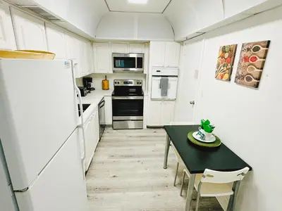 a white kitchen with a table and a refrigerator at Miami Hallandale Condo, Partial Ocean View Direct Beach and Pool Access Miami Hollywood Beach in Hollywood