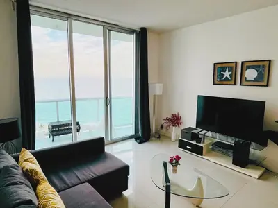 a living room with a couch and a view of the ocean at Miami Hallandale Condo, Partial Ocean View Direct Beach and Pool Access Miami Hollywood Beach in Hollywood