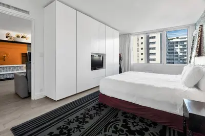 a white bedroom with a large bed and a tv at 1100 West South Beach Luxe Miami Condos by Joe Semary in Miami Beach