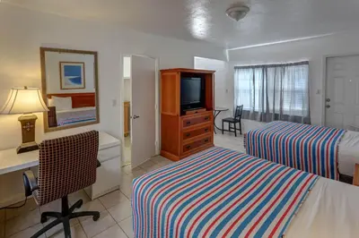 a hotel room with two beds and a desk and a television at Richard's Motel Courtyard in Hollywood