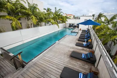 a swimming pool with lounge chairs and an umbrella on a building at Posh South Beach in Miami Beach