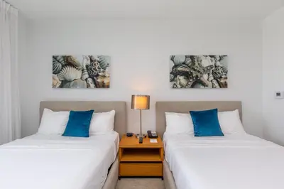 two beds with blue pillows in a hotel room at Private Ocean Luxury Condos at Beachwalk Resort in Hallandale Beach