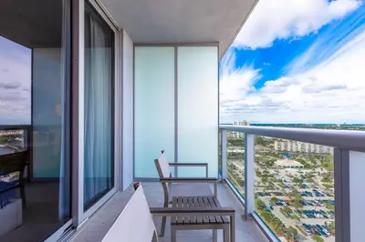 a balcony with a chair and a view of the city at Private Ocean Luxury Condos at Beachwalk Resort in Hallandale Beach