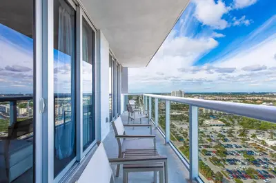 a balcony with two chairs and a view of a city at Private Ocean Luxury Condos at Beachwalk Resort in Hallandale Beach