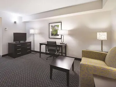 a hotel room with a couch and a desk and a television at La Quinta by Wyndham Plantation at SW 6th St in Plantation