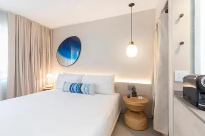 a white bedroom with a bed and a tv at Hotel Greystone - Adults Only in Miami Beach