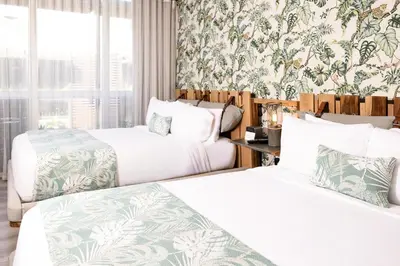 two beds in a hotel room with floral wallpaper at Lennox Miami Beach in Miami Beach