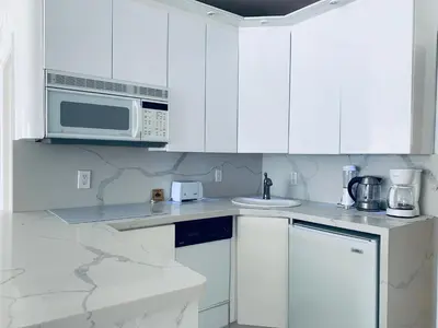 a white kitchen with a microwave and a sink at Sunrise Penthouse ocean view terrace beach few steps away SOBE in Miami Beach