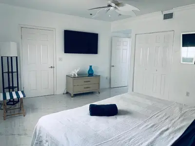 a white bedroom with a bed and a tv on the wall at Sunrise Penthouse ocean view terrace beach few steps away SOBE in Miami Beach