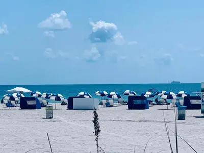 a beach with umbrellas and chairs on the sand at Sunrise Penthouse ocean view terrace beach few steps away SOBE in Miami Beach