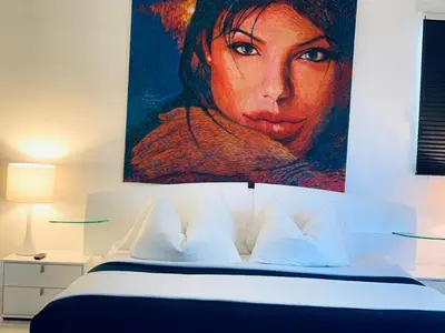 a bedroom with a large painting of a woman at Sunrise Penthouse ocean view terrace beach few steps away SOBE in Miami Beach